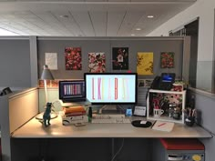 an office cubicle with two computer monitors on the desk and other items in front of it