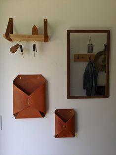 there are two pieces of leather hanging on the wall next to a mirror and coat rack