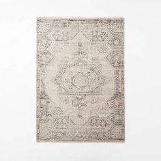 a beige rug with an intricate design on the bottom, and a white wall in the background