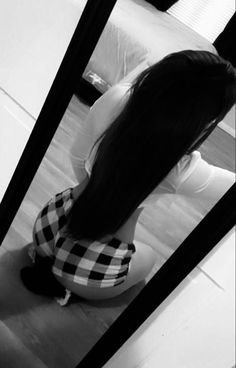 a woman sitting on the floor with her hair in ponytails looking at herself through a mirror