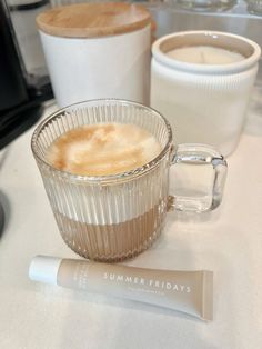 a cup of coffee sitting on top of a table next to a tube of lip bale