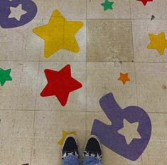 someone is standing on the floor with their feet up in front of colorful stars and numbers