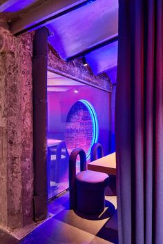 the interior of a restaurant with purple lighting and round chairs in front of a window