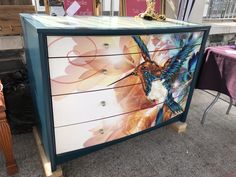 a dresser with a painting of a hummingbird on it's front and sides