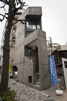 a building made out of concrete sitting next to a tree