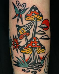 a mushroom tattoo on the left leg with flowers and butterflies around it, in front of a black background