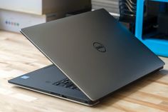 a laptop computer sitting on top of a wooden table next to a blue box and other electronics