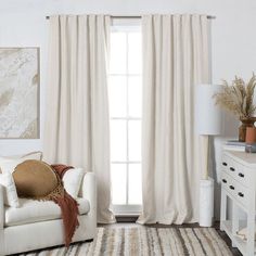 a living room with white furniture and curtains