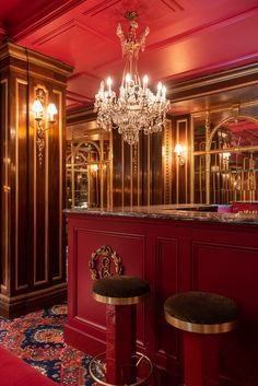 a red bar with two stools and a chandelier