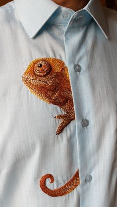 a man wearing a blue shirt with an orange chamelon embroidered on it