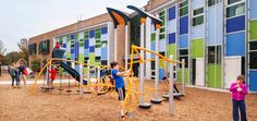 children are playing on the playground in front of a multi - colored building