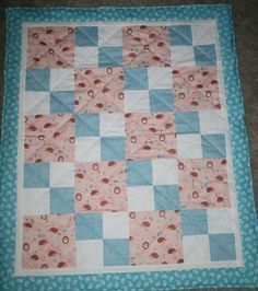 a blue and pink quilt on the floor with polka dots around it's edges