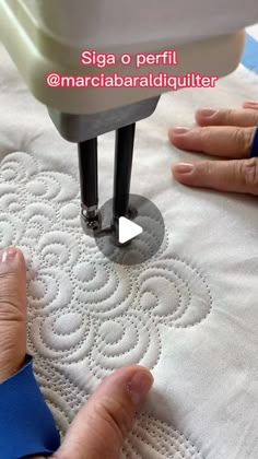 someone is using a sewing machine to sew on a piece of white fabric that has been embroidered onto it