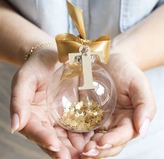 a person holding a glass ornament with a gold bow on it's ribbon