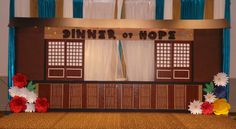 a stage set up for a dinner or hope event with paper flowers on the floor