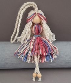 a doll with long hair and braids is hanging on a wall ornament