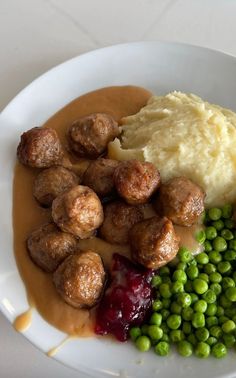 a white plate topped with meatballs, mashed potatoes and peas