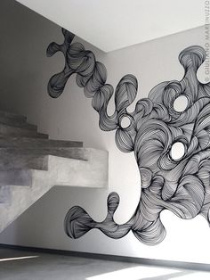 an artistically designed wall in the corner of a room with stairs leading up to it