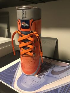 an orange nike sneaker is sitting on top of a cardboard box next to a can