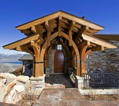 a stone and wood building with a wooden door on the front entrance, surrounded by large rocks