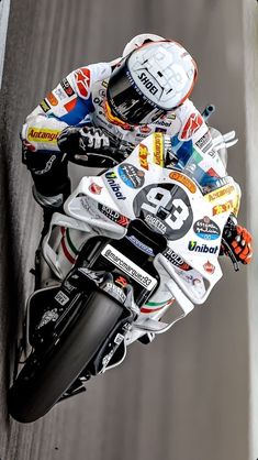 a man riding on the back of a motorcycle down a race track with lots of stickers