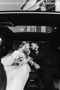 a bride and groom sitting in the back of a car