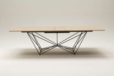 a wooden table with black metal legs and a wood top on an off white background