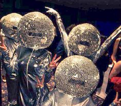 several people are standing in front of disco balls and holding their hands up to the ceiling