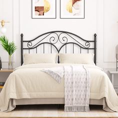 a bed with two pictures on the wall above it and a rug in front of it