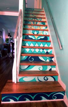 a stair case painted with blue and orange designs on it's sides, along with a wooden handrail