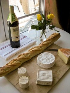 cheese, bread and wine are on a table