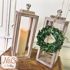 two wooden lanterns with wreaths on them sitting on a table next to each other