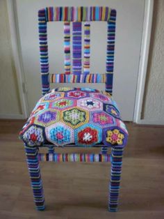 a multicolored crocheted chair sitting on top of a hard wood floor