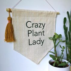 a sign that says crazy plant lady hanging on a wall next to a potted cactus