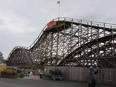 a man standing in front of a roller coaster