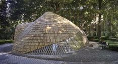 a building made out of bamboo sticks in the middle of a park