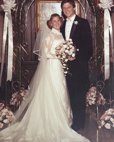 a bride and groom posing for a photo in front of an arch decorated with flowers