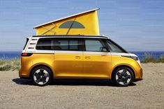 an electric car with a tent on top parked in the sand near the ocean and blue sky