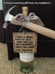 there is a bottle with a hammer on it and a sign that says, i have no idea what kind of house warming gift from my neighbors