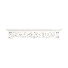 an ornate white shelf with carvings on the top and bottom, against a white background