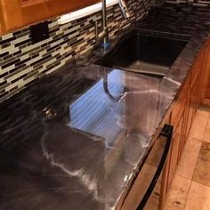 a kitchen with black counter tops and wooden cabinets, along with marble tile backsplash