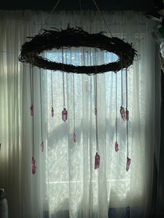 a wreath hanging from the ceiling in front of a window with beads and chains attached to it