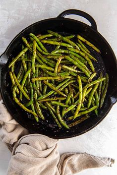 asparagus being cooked in a cast iron skillet on a white tablecloth