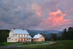 a large white house sitting on top of a lush green field under a cloudy sky