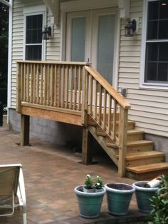 a porch with steps leading up to the front door and potted plants on the patio