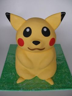 a yellow pokemon figurine sitting on top of a green surface with red eyes