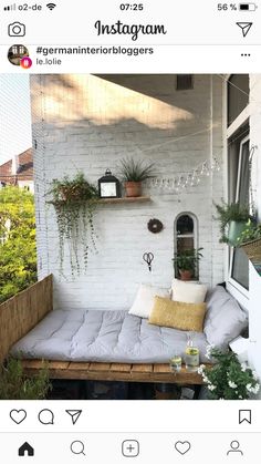 a white brick wall with some plants on it and a couch in the foreground