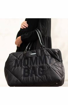 a woman carrying a black bag with the word mombag on it