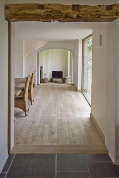 an open living room and dining area with wood flooring, white walls and wooden beams