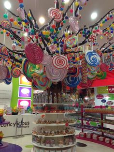 an assortment of lollipopo candies hanging from the ceiling in a store